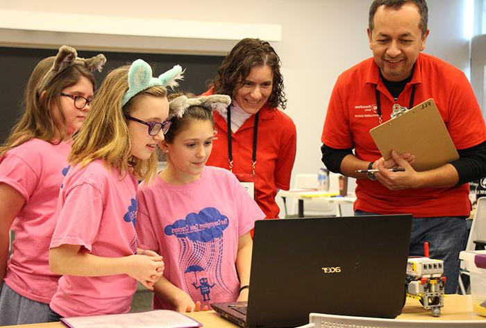 Professors Flavio Cabrera and Dr. Marietta Scanlon listen to a team's presentation on their robot's programming