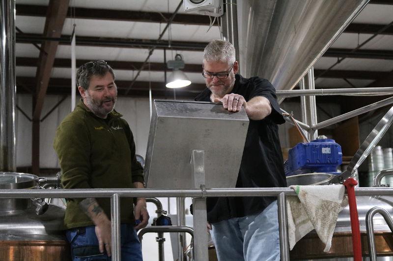 Two men looking thoughtfully at a screen in brewery