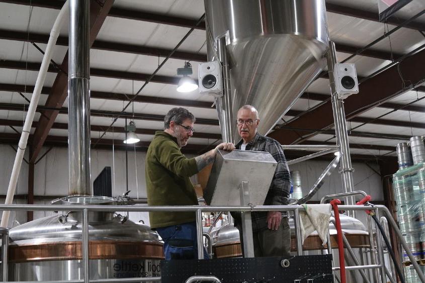 Two men in brewery looking thoughtful at screen